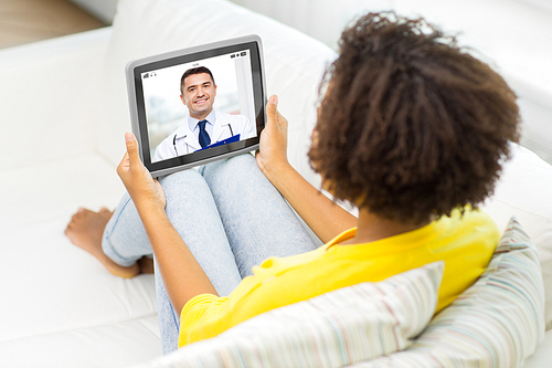 medicine, technology and healthcare concept - african american young woman or patient having video chat with doctor on tablet pc computer at home
