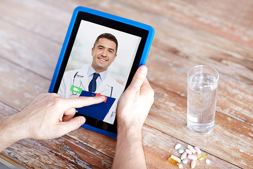 medicine, technology and healthcare concept - close up of patient with pills and water on table having video chat with doctor on tablet pc computer
