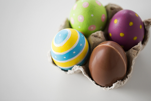 easter, holidays, tradition and object concept - close up of chocolate and colored eggs
