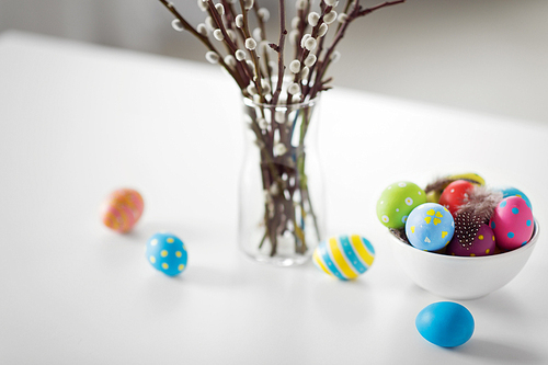 holidays and object concept - pussy willow branches and colored easter eggs in vase on table