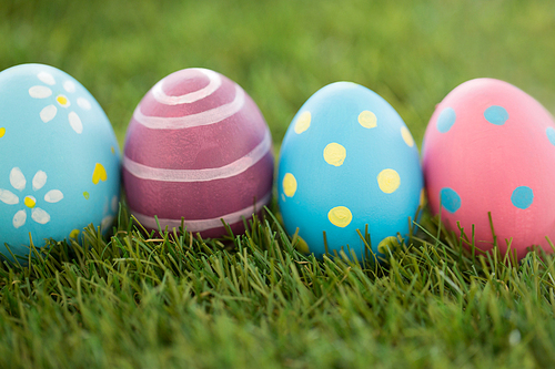 easter, holidays and tradition concept - row of colored eggs on artificial grass