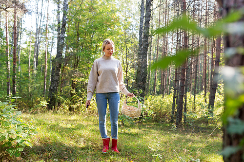 season and leisure people concept - young woman with wicker basket and knife picking mushrooms in forest