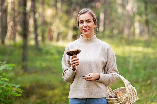 season and leisure people concept - young woman with basket and mushroom in autumn forest