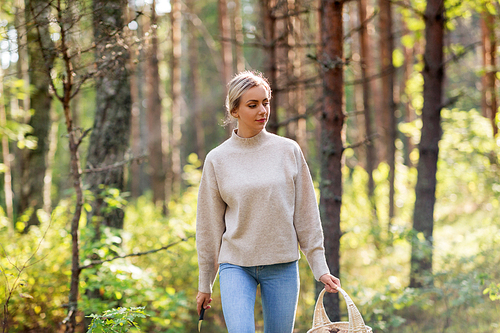 season and leisure people concept - young woman with wicker basket and knife picking mushrooms in forest