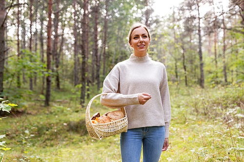 season and leisure people concept - young woman with mushrooms in wicker basket in forest