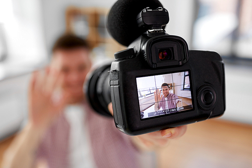 blogging, videoblog and people concept - close up of camera recording smiling male video . waving hand at home office