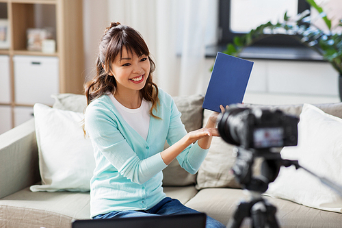 blogging, technology, videoblog and people concept - happy smiling asian woman or . with camera recording video blog of book review at home