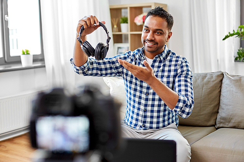 blogging, videoblog and people concept - indian male . with camera recording video review of headphones at home