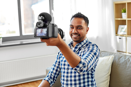 blogging, videoblog and people concept - smiling indian male video . with camera videoblogging at home