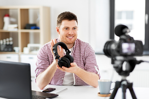 blogging, videoblog and people concept - male . with camera recording video review about headphones at home office