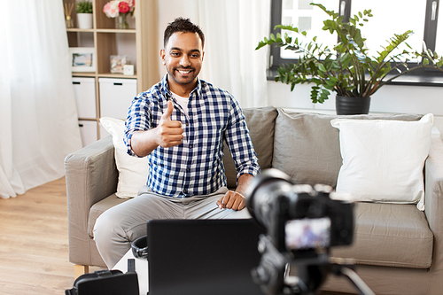 blogging, videoblog and people concept - indian male . with camera recording video blog and showing thumbs up at home