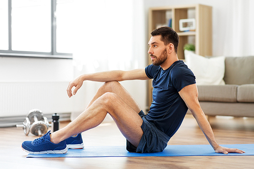 sport, fitness and healthy lifestyle concept - man resting on exercise mat at home