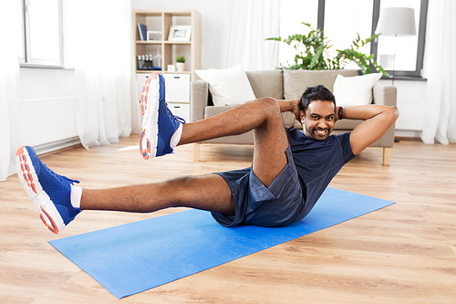 sport, fitness and healthy lifestyle concept - indian man making abdominal exercises at home