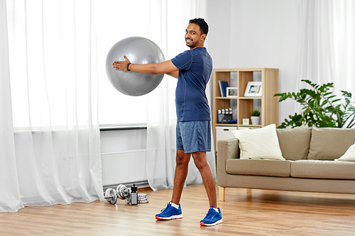 fitness, sport and healthy lifestyle concept - smiling indian man exercising with ball at home