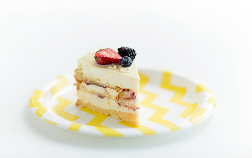 party food, junk-food and sweets concept - piece of delicious berry layer cake on disposable plate over white background