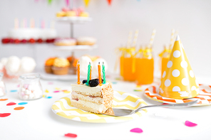 food, celebration and festive concept - piece of cake with candles on plate at birthday party