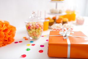 party and festive concept - close up of birthday present in orange wrap on table