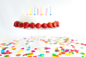 food, dessert and party concept - close up of birthday cake with candles and strawberries on stand