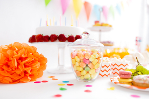 food, confectionery and sweets concept - glass jar with colorful candy drops at birthday party