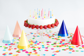food, dessert and party concept - birthday cake with candles and strawberries on stand