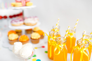 birthday party and drinks concept - orange juice in glass bottles with paper straws on table
