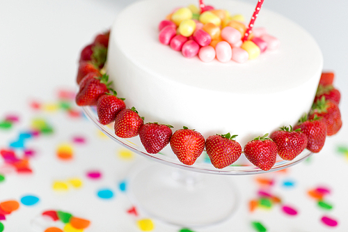 food, dessert and party concept - close up of birthday cake with strawberries on stand