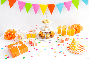 party food and festive concept - birthday present, garland, drinks and treats on table