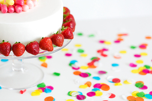 food, dessert and party concept - close up of birthday cake with strawberries on stand