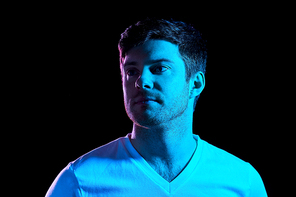 people concept - portrait of young man in t-shirt over ultra violet neon lights in dark room