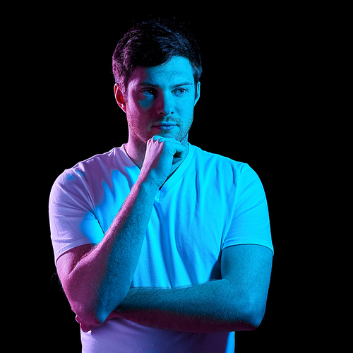 people concept - portrait of young man in t-shirt over ultra violet neon lights in dark room