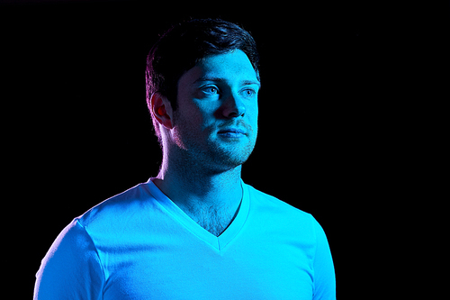 people concept - portrait of young man in t-shirt over ultra violet neon lights in dark room