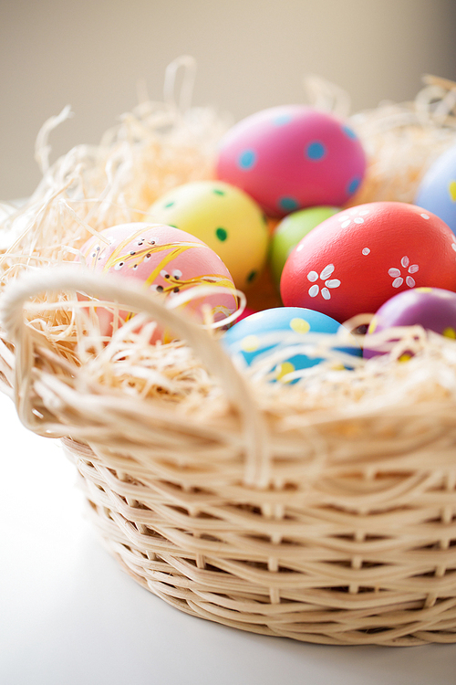 easter, holidays, tradition and object concept - close up of colored eggs in basket
