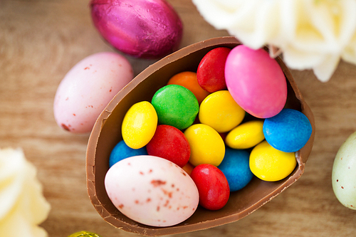 easter, junk-food, confectionery and unhealthy eating concept - close up of chocolate egg and candy drops on table