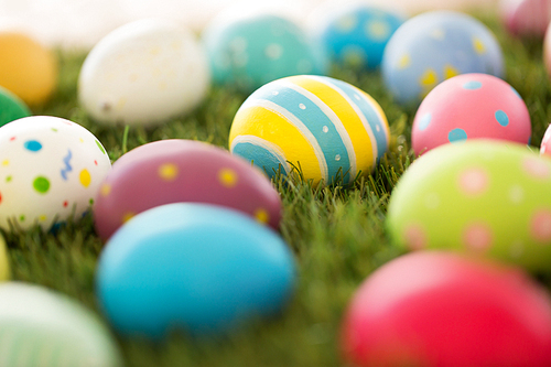 easter, holidays and tradition concept - colored eggs on artificial grass