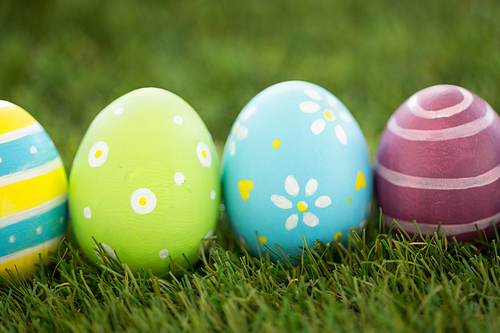 easter, holidays and tradition concept - row of colored eggs on artificial grass