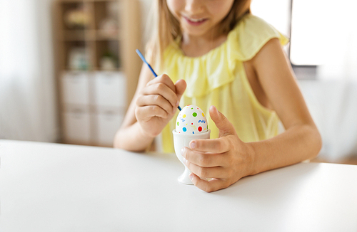 easter, holidays and people concept - close up of girl coloring egg by paintbrush
