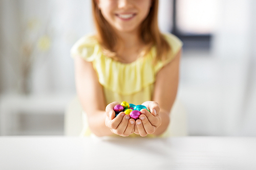 easter, holidays and people concept - close up of happy girl holding chocolate eggs in colorful foil wrappers
