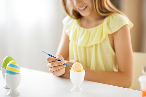 easter, holidays and people concept - close up of girl coloring egg by paintbrush