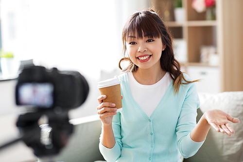 blogging, technology, videoblog and people concept - nice asian woman or . with camera and takeaway coffee cup recording video blog at home in morning