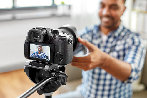 blogging, videoblog and equipment concept - close up of smiling indian male video . adjusting camera at home