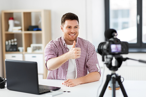 blogging, videoblog and people concept - male . with camera recording video blog and showing thumbs up at home office