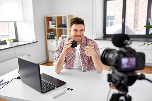 blogging, videoblog and people concept - male . with camera recording video review of smart speaker and showing thumbs up gesture at home office