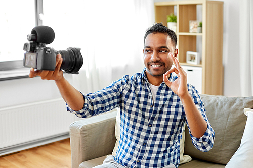 blogging, videoblog and people concept - smiling indian male video . with camera videoblogging making ok gesture at home