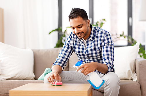 household and people concept - indian man cleaning table with detergent at home