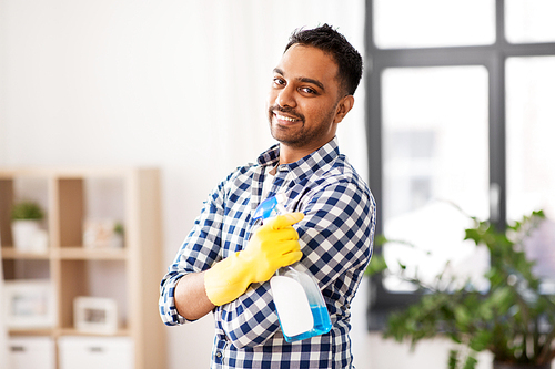 cleaning, housework and housekeeping concept - smiling indian man with detergent at home
