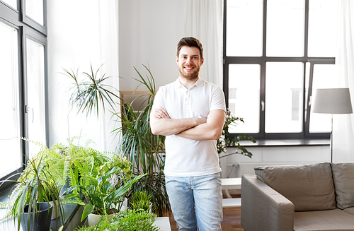 people, nature and plants concept - smiling man with houseplants at home