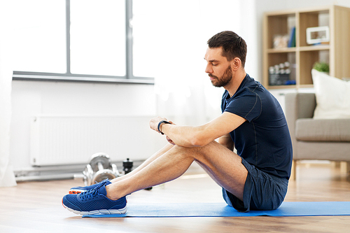 sport, technology and healthy lifestyle concept - man with fitness tracker exercising at home