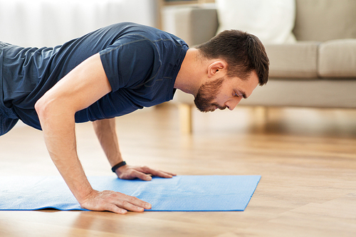 fitness, sport, training and concept - man doing push ups at home