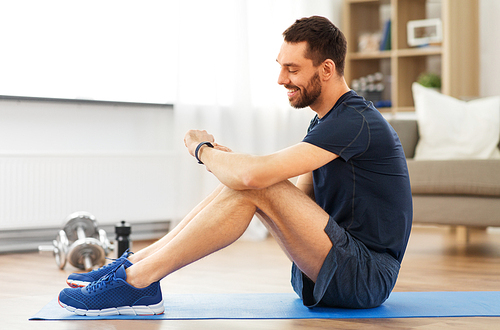 sport, technology and healthy lifestyle concept - smiling man with fitness tracker exercising at home