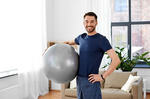 fitness, sport and healthy lifestyle concept - man exercising with ball at home